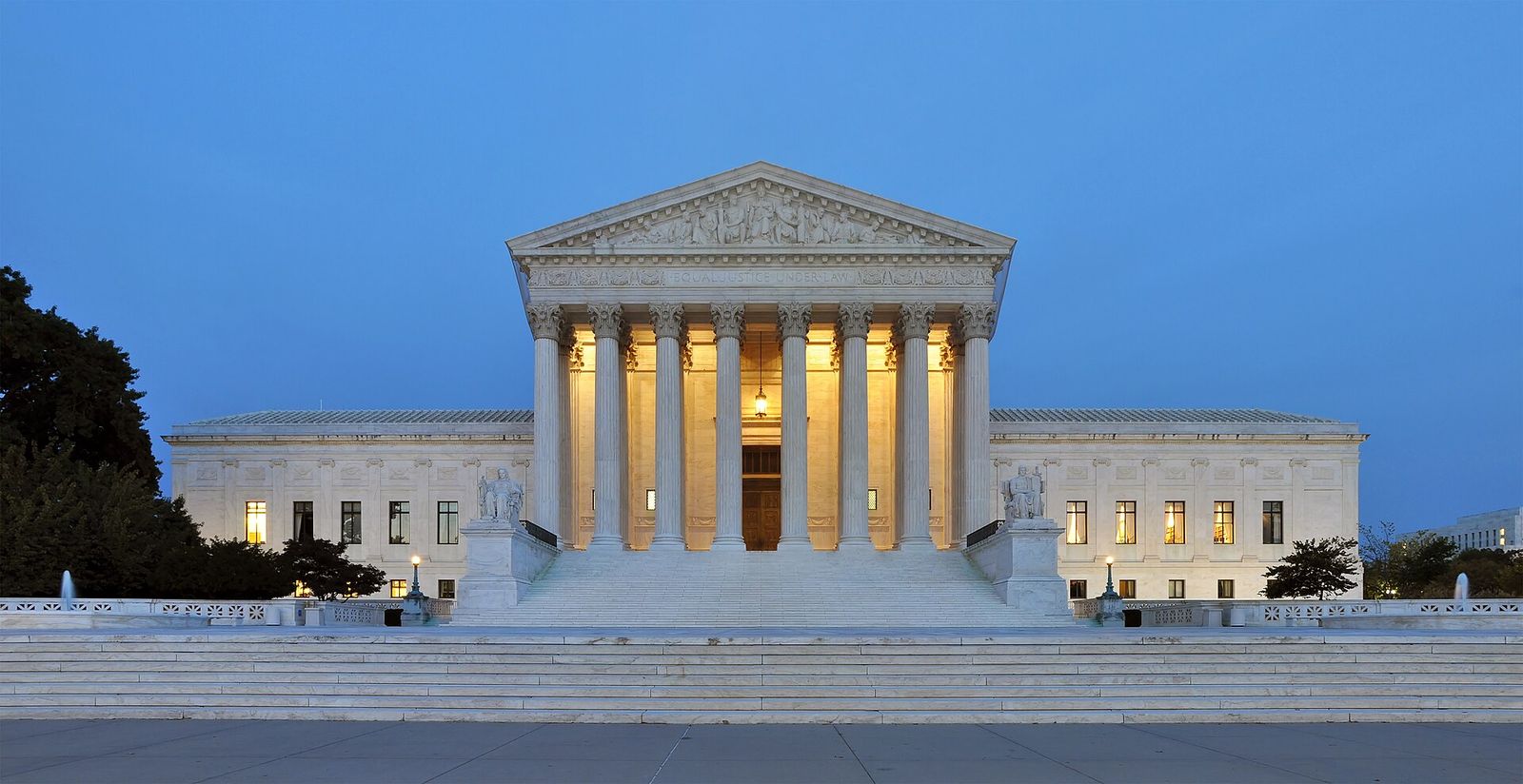 The west facade of the United States Supreme Court building lit up at dusk.