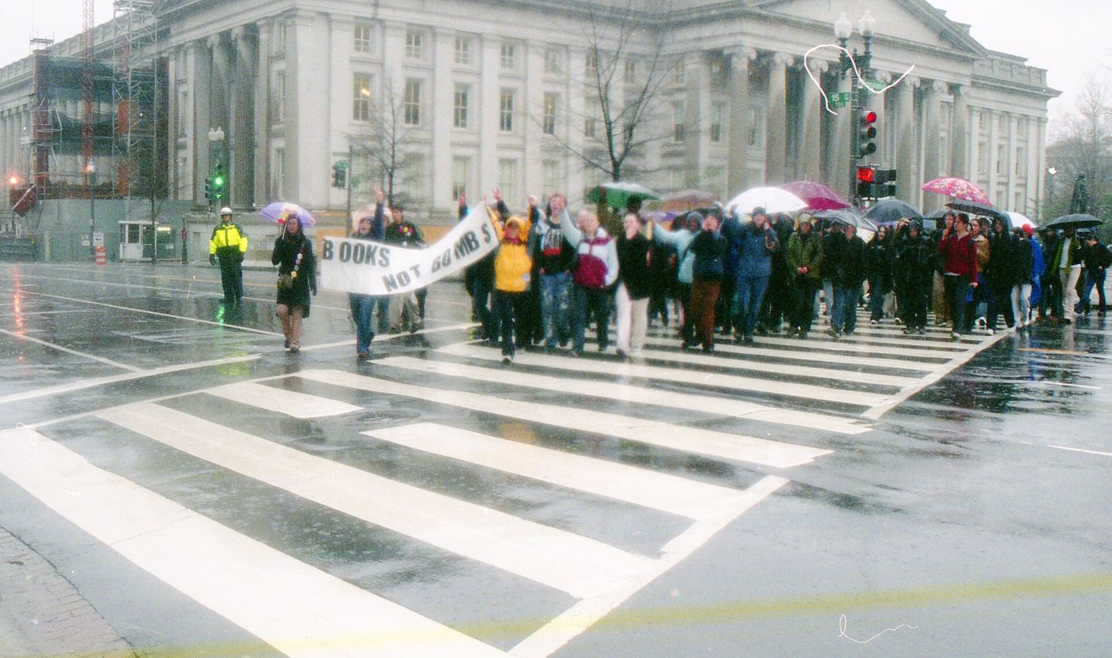 Anti-war marchers carrying a 'Books not bombs' banner across a rainy Washington street.