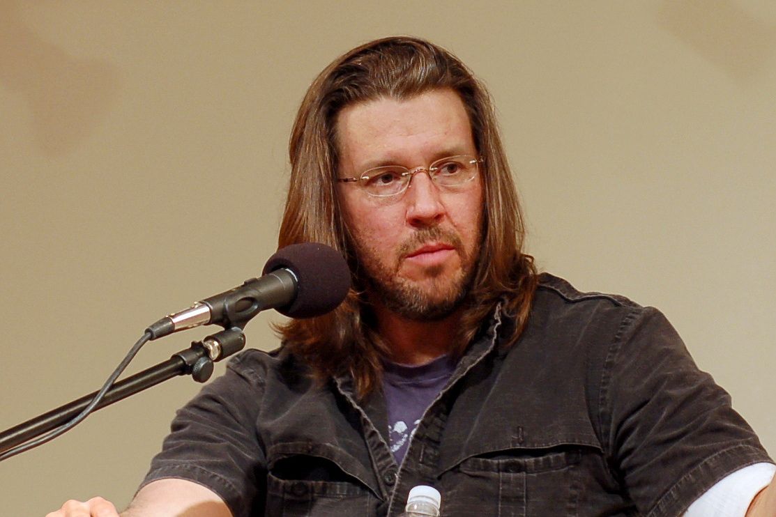 David Foster Wallace speaking at a podium with a microphone.