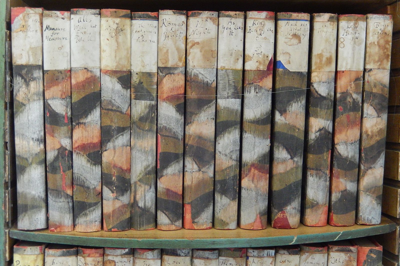 A shelf of Shakespeare's plays in hand-bound volumes with marbled paper covers.